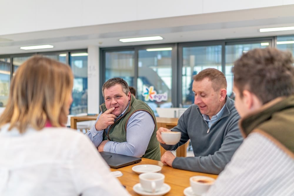 Mae tîm Baileys yn sgwrsio o amgylch bwrdd wrth yfed coffi